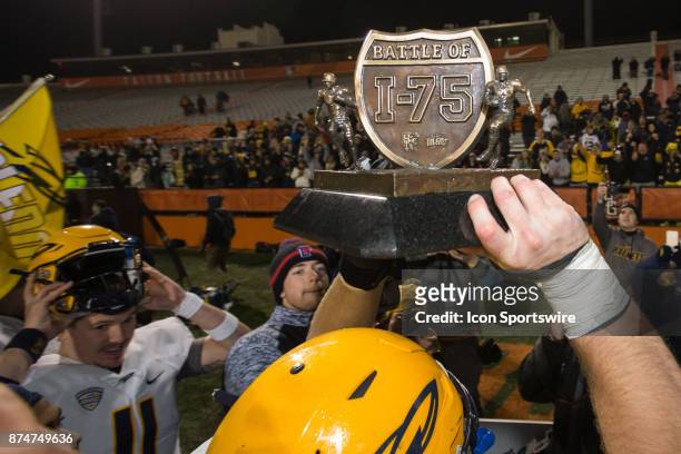 Toledo player holds the Battle of I-75 trophy up at the conclusion of the game between the Toledo Rockets and the Bowling Green Falcons on November...