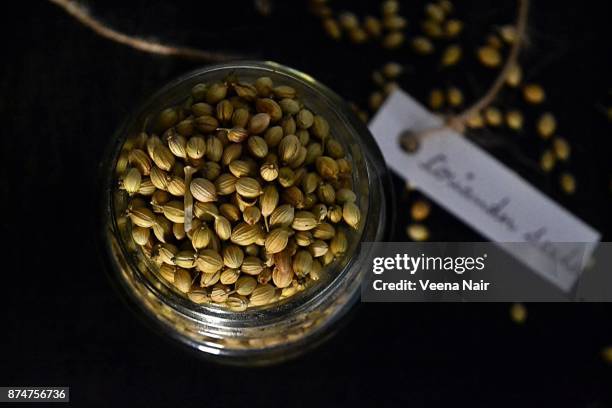 coriander seeds in a glass jar with handwritten tag/label - koriander stock-fotos und bilder