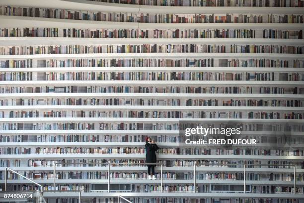 This picture taken on November 14, 2017 shows a woman taking pictures at the Tianjin Binhai Library. A futuristic Chinese library has wowed book...