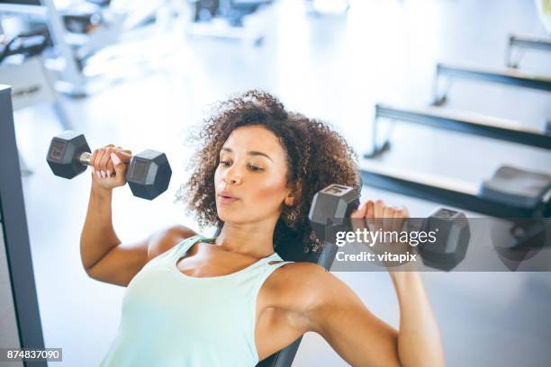 junge frau weighraining im gym - dumbells stock-fotos und bilder