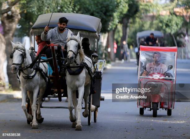 People ride their electric-powered tricycles as a phaeton passes near them on an autumn day in Buyukada of Prince Islands of Istanbul, Turkey on...