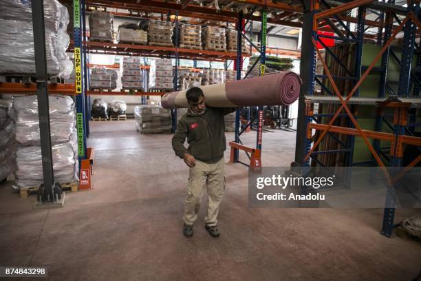 Man carries a carpet as relief supply kits including food, water, clothes and many other humanitarian aids provided by Humanitarian Relief Foundation...