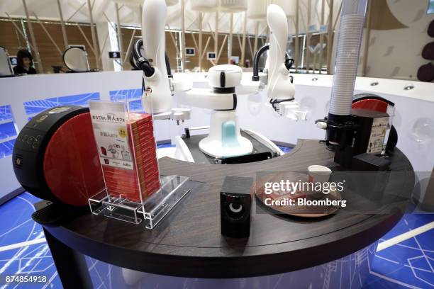 Kawasaki Heavy Industries Ltd. Two-armed duAro robot stands behind a counter serving coffees from Nestle SA Nescafe Gold Blend Barista 50 coffee...