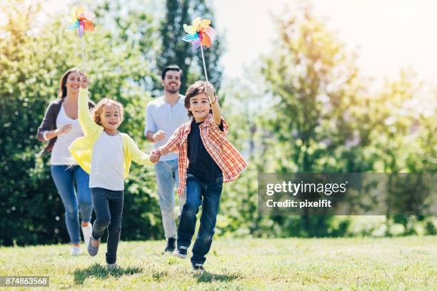 junge familie spielen im park - windrad stock-fotos und bilder