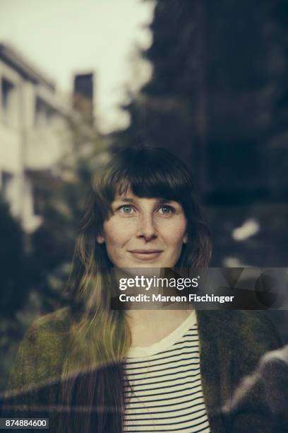 confident woman looking out of window - mareen fischinger stock-fotos und bilder