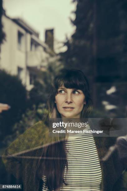 sceptical woman looking out of window - mareen fischinger stock-fotos und bilder