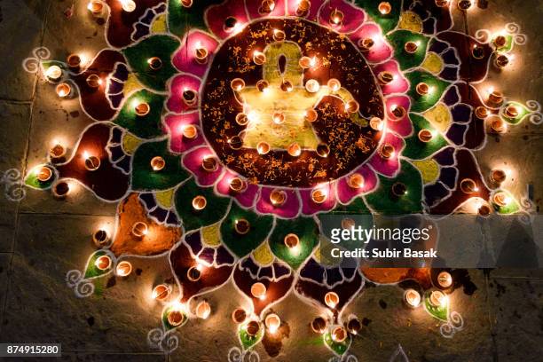 woman arranging oil lamps on rangoli during diwali. - rangoli stock-fotos und bilder