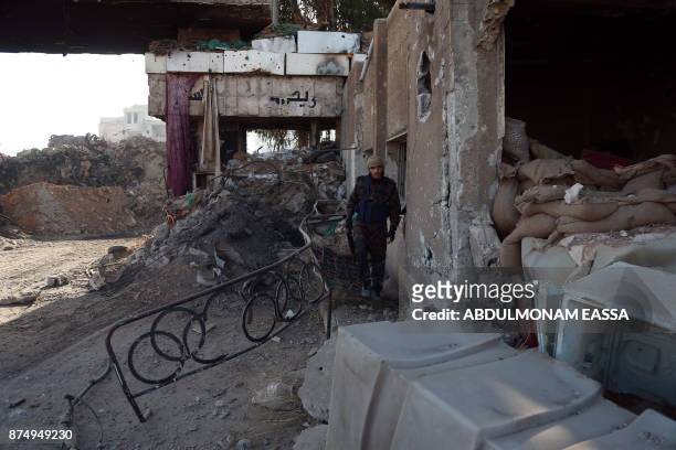 Rebel fighter from the Ahrar al-Sham brigade walks past the debris of damaged buildings in the rebel-held besieged town of Harasta, in the Eastern...