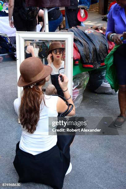 Chinese tourist tries on a hat for sale at a flea market in the Chelsea district of New York City.