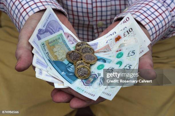 pound coins and british pound notes in man's hands. - money uk foto e immagini stock