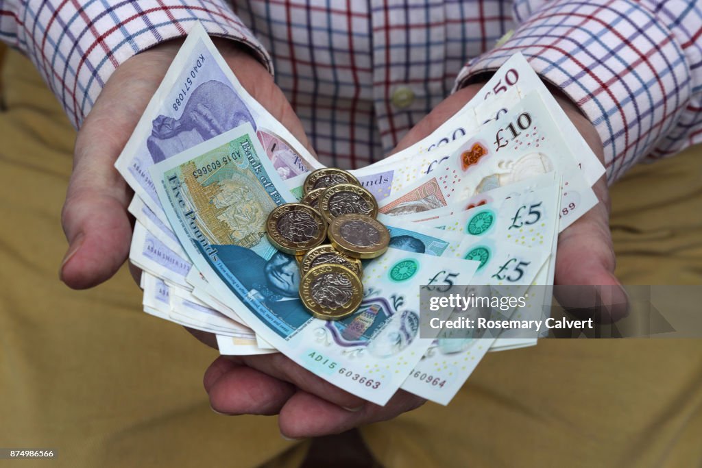 Pound coins and British pound notes in man's hands.
