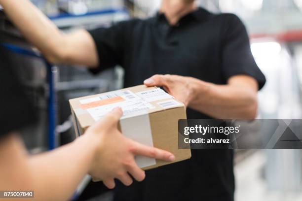 arbeiter, die übergabe eines pakets an kollegen - delivery driver stock-fotos und bilder