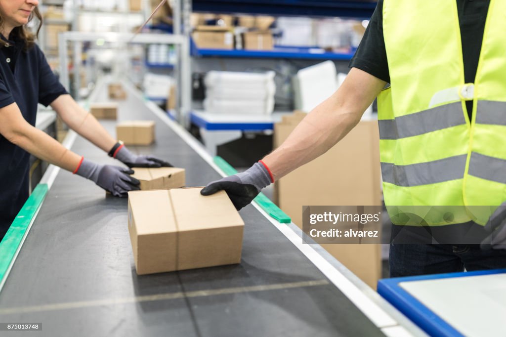 Trabajadores que trabajan en banda transportadora en planta de envasado