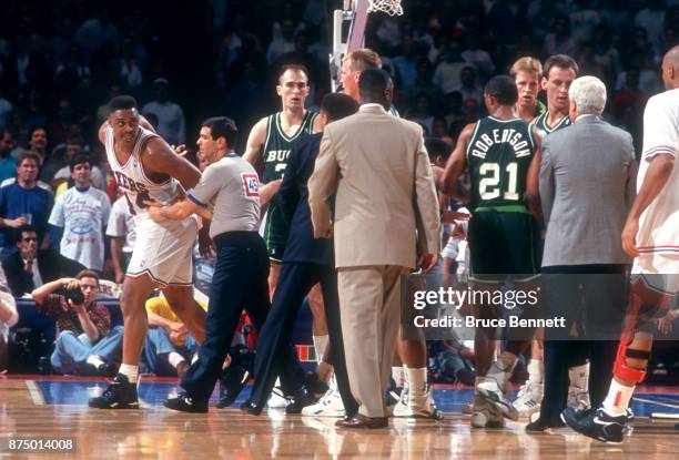 Rick Mahorn of the Philadelphia 76ers is held back by referee Joe Forte after fighting with Alvin Robertson of the Milwaukee Bucks during Game 3 of...