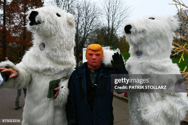 Picture taken on November 16, 2017 shows people dressed up in polar bear costumes and a man with a mask of US president Donald Trump during a...