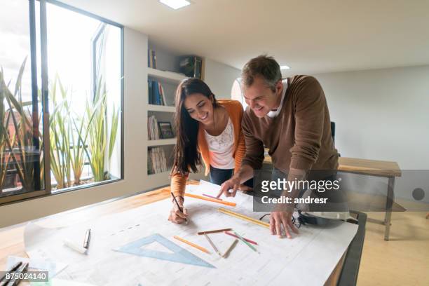 coppia di architetti che lavorano in ufficio disegnando un progetto - veduta di interni foto e immagini stock