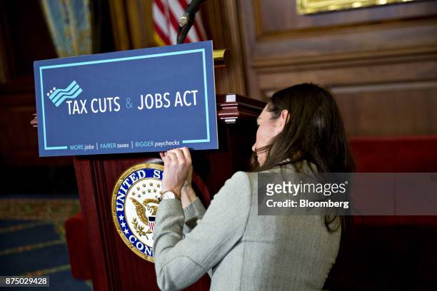 Staff member places a "Tax Cuts and Jobs Act" sign on a podium before a news conference with House Republican members after voting on the tax reform...