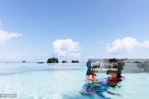 mother and child having intimate moment in clear tropical water, japan - agua estancada fotografías e imágenes de stock
