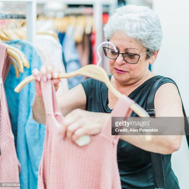 銀の髪の 65 歳アクティブ シニア女性、衣料品小売店でのショッピング - ライツヴィルビーチ ストックフォトと画像