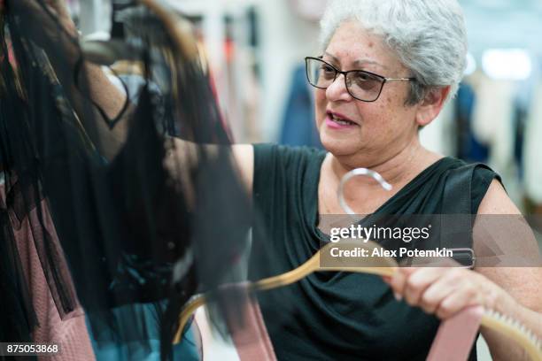 o prata-65 anos de idade ativo sênior mulher cabelos compras em loja de varejo de roupas - 65 69 years - fotografias e filmes do acervo