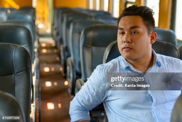 young handsome asian tourist man riding the train at the railway station - train interior stock pictures, royalty-free photos & images