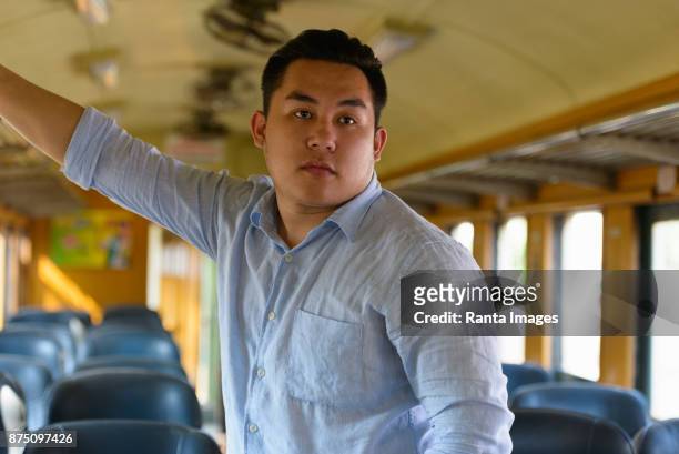 young handsome asian tourist man riding the train at the railway station - grab handle stock pictures, royalty-free photos & images