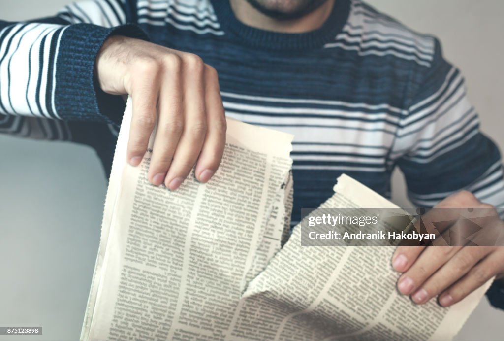 Fake news. Man tearing newspaper.