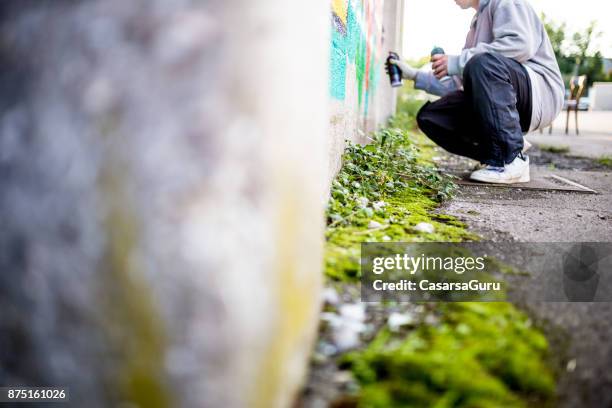 late tiener graffiti kunstenaar tekening graffiti op muur - vandalisme stockfoto's en -beelden