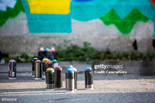 spray cans on the floor in front of graffiti on the wall - spray bottle stock pictures, royalty-free photos & images