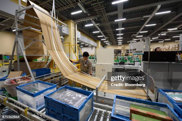 Yamato Logistics Co. Employee feeds cardboard sheets into the Neopost SA CVP-500 automated packing system during a demonstration at the Yamato...