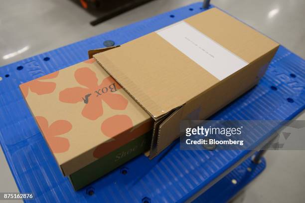 Shoe box, left, and cardboard box prepared by the Neopost SA CVP-500 automated packing system sits on a cart during a demonstration at the Yamato...