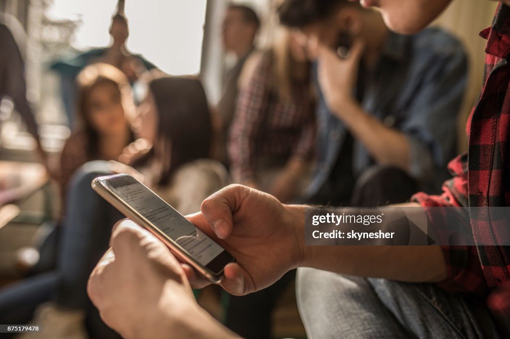 Close up of unrecognizable student using cell phone on a break in the classroom.