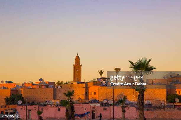 marrakech cityscape during sunset taken from building terrace with mosque silhouettes and nice colors in the sky during travel vacations in morocco. - marrakech fotografías e imágenes de stock