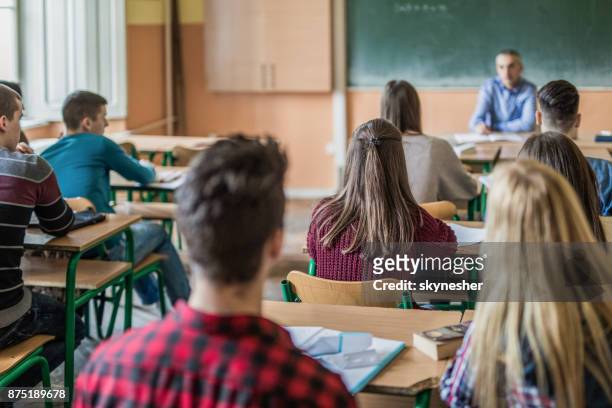 achteraanzicht van middelbare scholieren voor het bijwonen van een klasse. - school teacher stockfoto's en -beelden