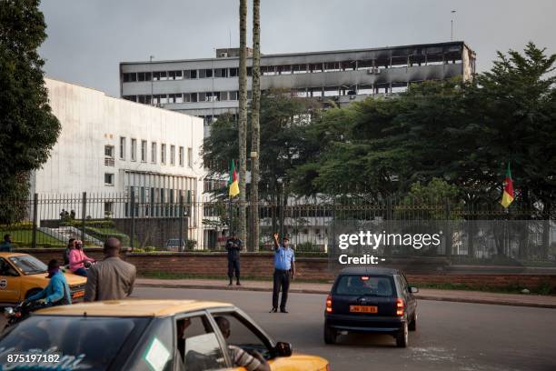 Policeman controls traffic in front of the damaged building of Cameroon's parliament on November 17, 2017 in Yaounde, after a fire swept through the...