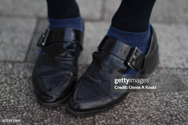 Close of Aki's shoes. Aki stops for a quick fashion snap wearing a grey Jóueie t-shirt featuring a gold cupid on a cross suspended in resin with...