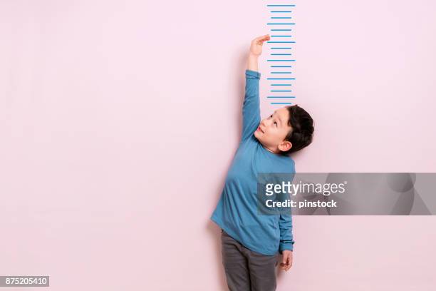 child measuring his height - childhood stock pictures, royalty-free photos & images
