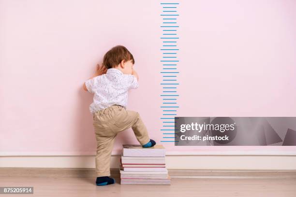 child measuring his height - height chart stock pictures, royalty-free photos & images