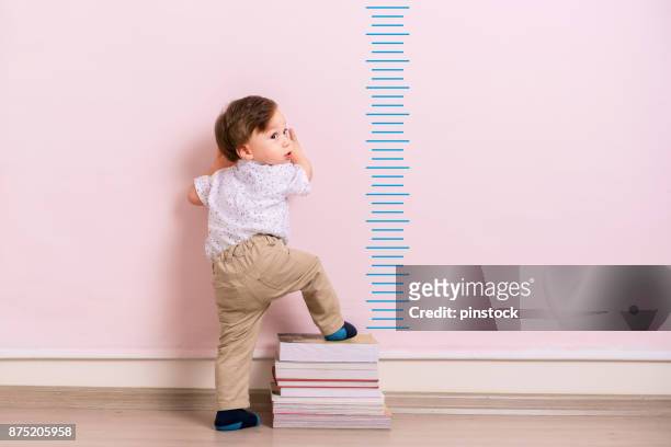child measuring his height - height chart stock pictures, royalty-free photos & images