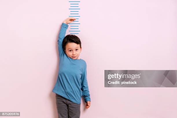 child measuring his height - kids growth chart stock pictures, royalty-free photos & images