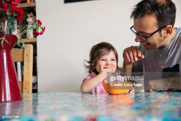 a young girl happily enjoying snack time with her dad - snapshot of britain fotografías e imágenes de stock