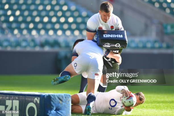 England's fly-half George Ford tackles England's centre Owen Farrell over England's Danny Care a training session at Twickenham Stadium in southwest...