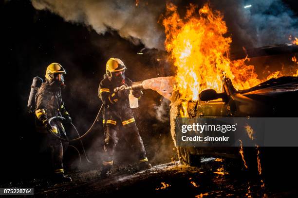 firefighters spraying water on burning car - heroes after dark stock pictures, royalty-free photos & images