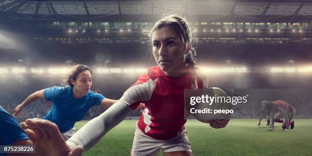 woman rugby player beating rival players during match in stadium - female rugby stock pictures, royalty-free photos & images