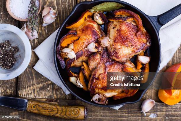 roast chicken legs with pumpkin in cast iron skillet - hähnchen grill stock-fotos und bilder