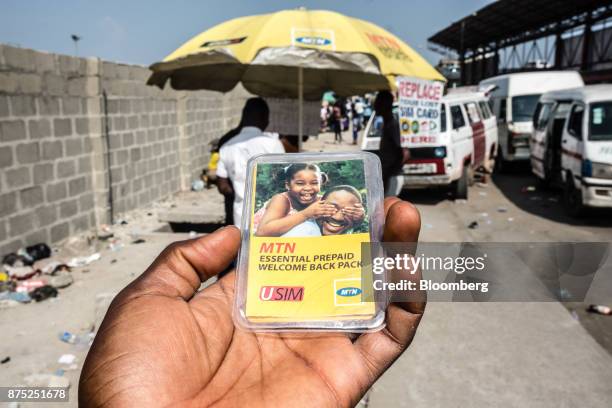 An MTN Group Ltd. Pre-paid SIM card packet is held at a roadside kiosk in this arranged photo in Lagos, Nigeria, on Monday, Nov. 13, 2017. MTN is...