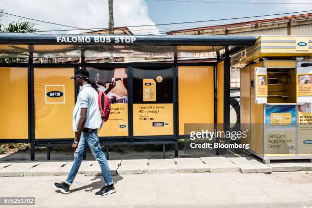 Pedestrian passes by an MTN Group Ltd. Bus stop advertisement and roadside kiosk in Lagos, Nigeria, on Monday, Nov. 13, 2017. MTN is focused on...