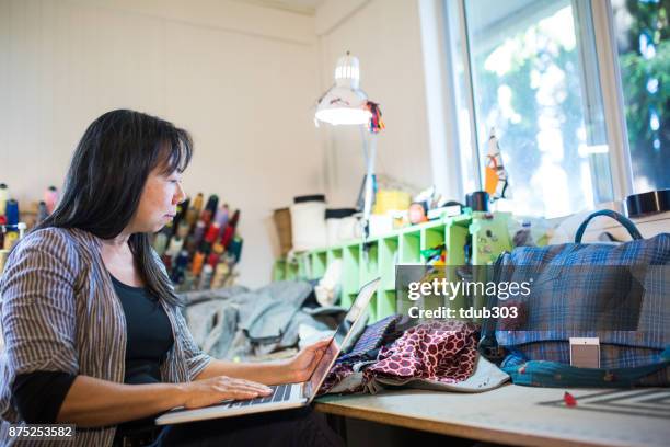 ein reifen textil-unternehmer arbeiten auf einem laptopcomputer in ihrem atelier - insel salt spring island stock-fotos und bilder