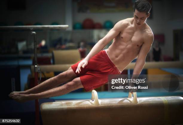 young gymnast exercising at pommel horse - male gymnast stock pictures, royalty-free photos & images