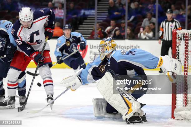 Cleveland Monsters right wing Miles Koules attempts to redirect the puck as Milwaukee Admirals goalie Juuse Saros swipes at the puck with his stick...